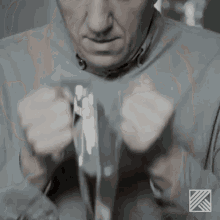 a man in a grey shirt is tying a tie with his hands