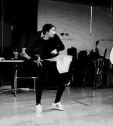 a black and white photo of a woman dancing in front of a mirror