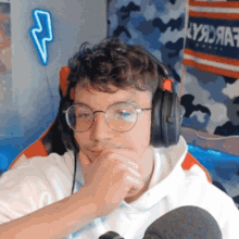 a young man wearing headphones and glasses is sitting in front of a lightning bolt sign