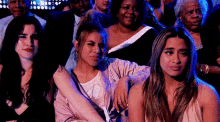 a group of women are sitting in a crowd watching a performance .