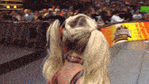a woman in a ponytail stands in front of a crowd at a wrestling event