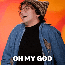 a man wearing a beanie and a denim jacket is laughing with the words oh my god below him