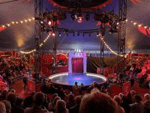 a crowd of people watching a circus show with a red star in the middle