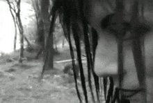 a black and white photo of a woman 's face behind bars in the woods .