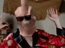 a man in a robe and sunglasses is wearing a giant thumb on his face .