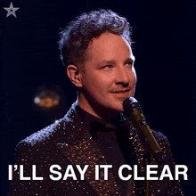 a man singing into a microphone with the words " i 'll say it clear " next to him