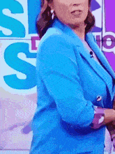 a woman in a blue jacket is standing in front of a sign that says s