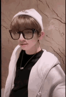 a young man wearing glasses and a beanie is taking a picture of himself .