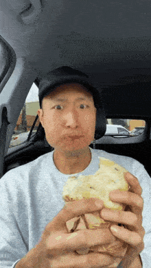 a man in a car is eating a sandwich with his mouth open