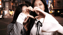 two girls are making a heart with their hands