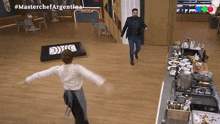 a man and a woman are dancing in a kitchen with the words masterchef argentina in the corner
