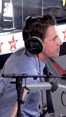 a man wearing headphones stands in front of a sign that says virgin radio