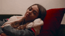 a young woman is laying on a couch with a red pillow