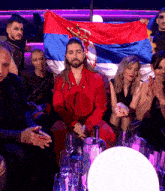 a group of people sitting around a table with a man holding a flag