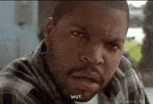 ice cube is wearing a plaid shirt and making a funny face with his mouth open .