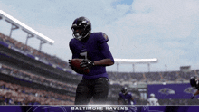 a baltimore ravens player is holding a football in a stadium