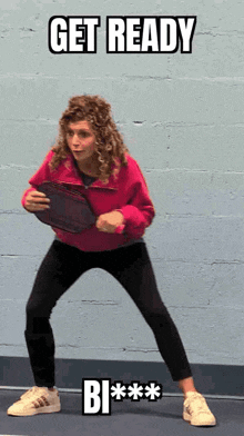 a woman in a pink jacket is holding a tennis racquet and says get ready
