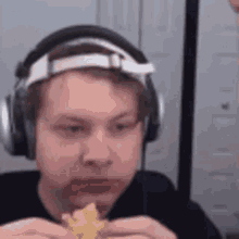 a man wearing headphones and a headband is eating a hamburger .