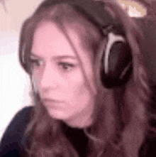 a close up of a woman wearing headphones making a funny face .