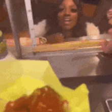 a woman is looking through a window at a chicken nugget display .