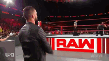 a wrestler stands in front of a raw sign