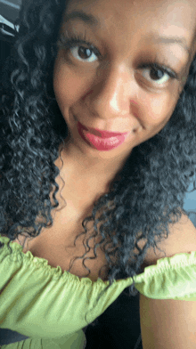 a woman with curly hair is smiling and wearing a green top