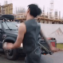 a man in a sleeveless shirt is standing in front of a car .