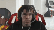 a young man wearing headphones and a headset is sitting in a gaming chair .