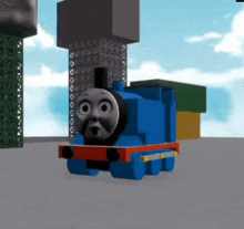 a blue train with a face on it is standing in front of a building .