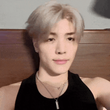 a close up of a person wearing a black tank top and a silver necklace