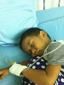 a young boy is laying in a hospital bed with an iv on his arm