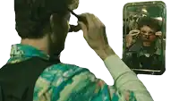 a man in a blue shirt is looking at himself in the mirror