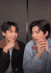 two young men are sitting next to each other and one of them is wearing a jacket that says supreme