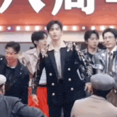 a group of young men are standing in front of a crowd of people .