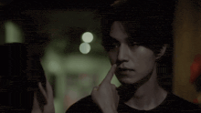 a man is touching another man 's face in a dark room .