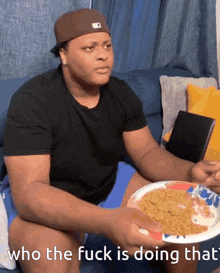 a man sitting on a couch holding a plate of food with the words " who the fuck is doing that " above him
