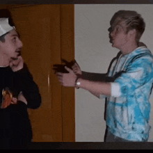 two men are standing next to each other and one is wearing a blue tie dye shirt .