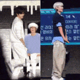two men are standing next to each other on a stage and one is wearing a hat .