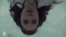 a woman is laying upside down in the snow with a sy fy logo in the corner