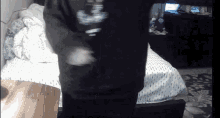 a person standing in front of a bed wearing a black shirt that says ' nc ' on it