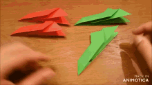 a red and green paper airplane are being made on a wooden table