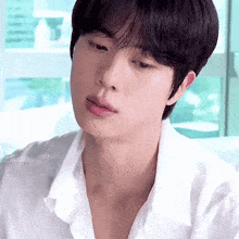 a close up of a young man 's face with a white shirt on