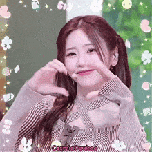 a girl is making a heart shape with her hands and the name cosmic deukae is on the bottom
