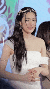 a woman in a white dress with a tiara on her head smiles