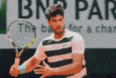 a man is holding a tennis racquet in front of a bnp par logo