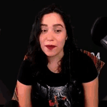 a woman is smiling in front of a microphone and wearing a black shirt .