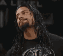 a man with long hair and a beard is wearing a black shirt and a black jacket .
