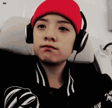 a man wearing headphones and a red beanie is sitting on a chair