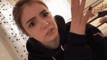a girl in a black sweatshirt is making a face