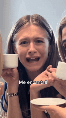 a girl is holding a cup with the words me encanta written on it
